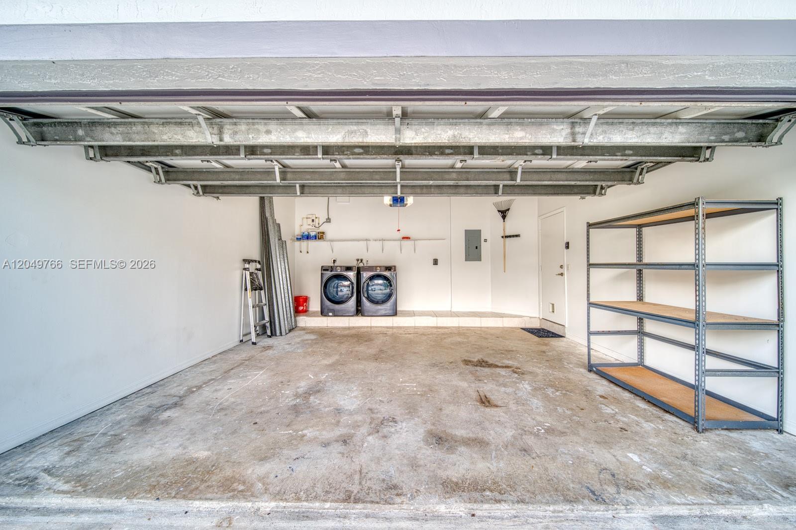 This garage features a concrete floor, a metal shelving unit, and a laundry area — 15950 SW 71st Ter, Miami FL 33193, MIAMI, FL