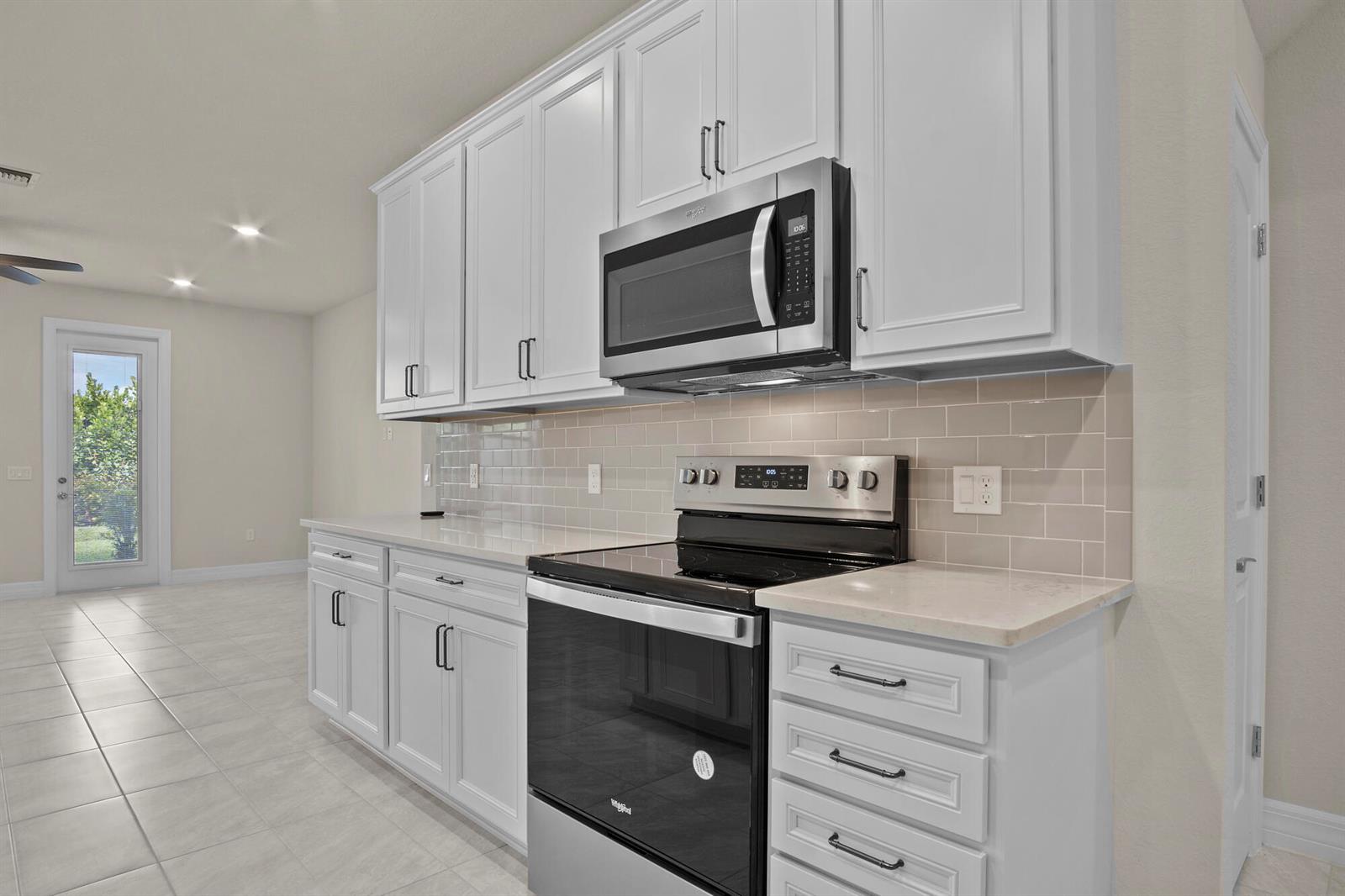 A kitchen features white cabinets, stainless steel appliances, a subway tile backsplash, and light countertops — 4837 Chantilly Road, Lake Worth FL 33467, LAKE WORTH, FL