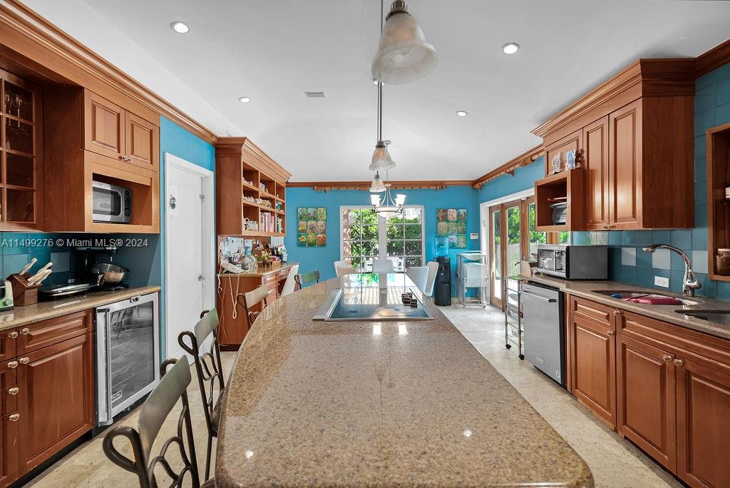 A kitchen features wood cabinets, a large granite island, and bright blue walls — 61 Camden Ct, Bal Harbour FL 33154, BAL HARBOUR, FL
