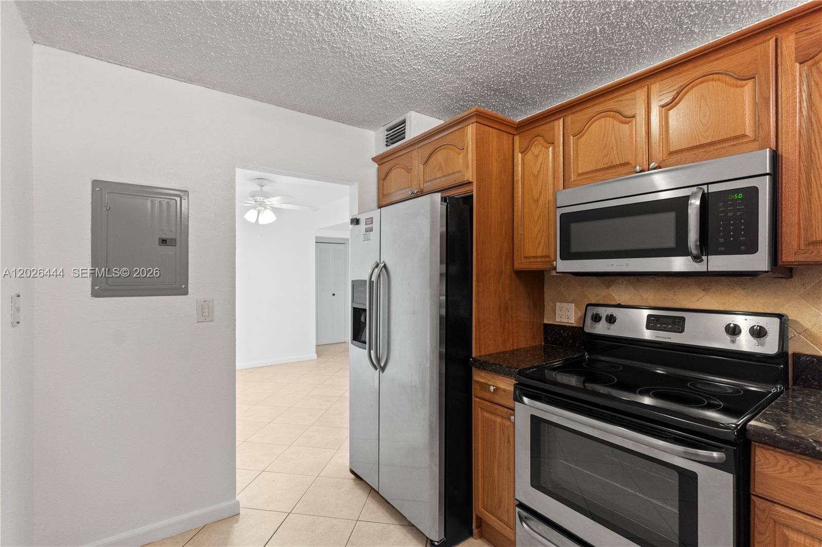 A kitchen features wooden cabinets, stainless steel appliances, and a tiled floor — 7100 NW 17th St # 219, Plantation FL 33313, PLANTATION, FL