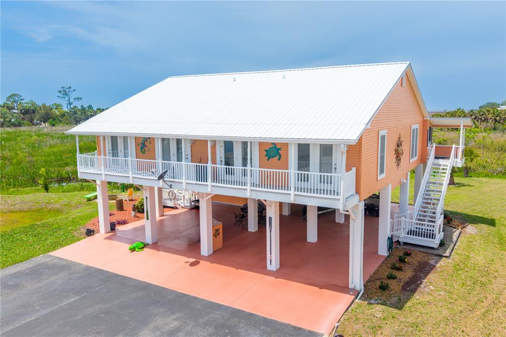 An elevated house with orange siding, a white metal roof, and a large covered patio — 200/202 NE 205TH STREET, SUWANNEE, FL