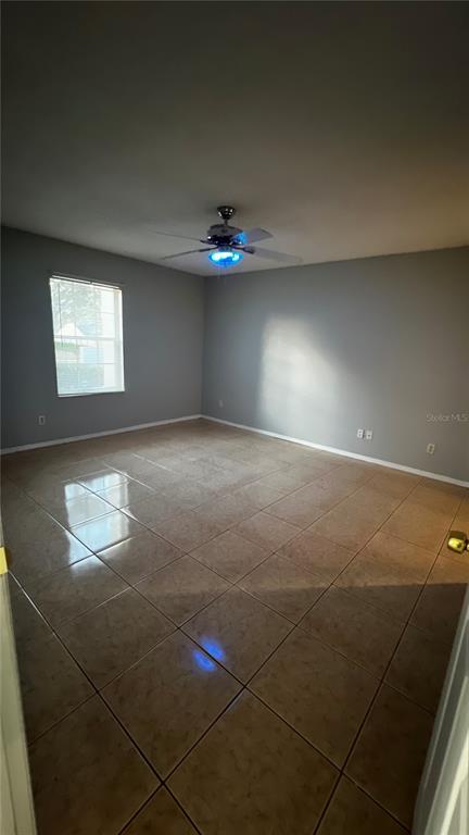 An empty room with light gray walls, tan tile flooring, and a ceiling fan — 6409 ROYAL TERN STREET, ORLANDO, FL