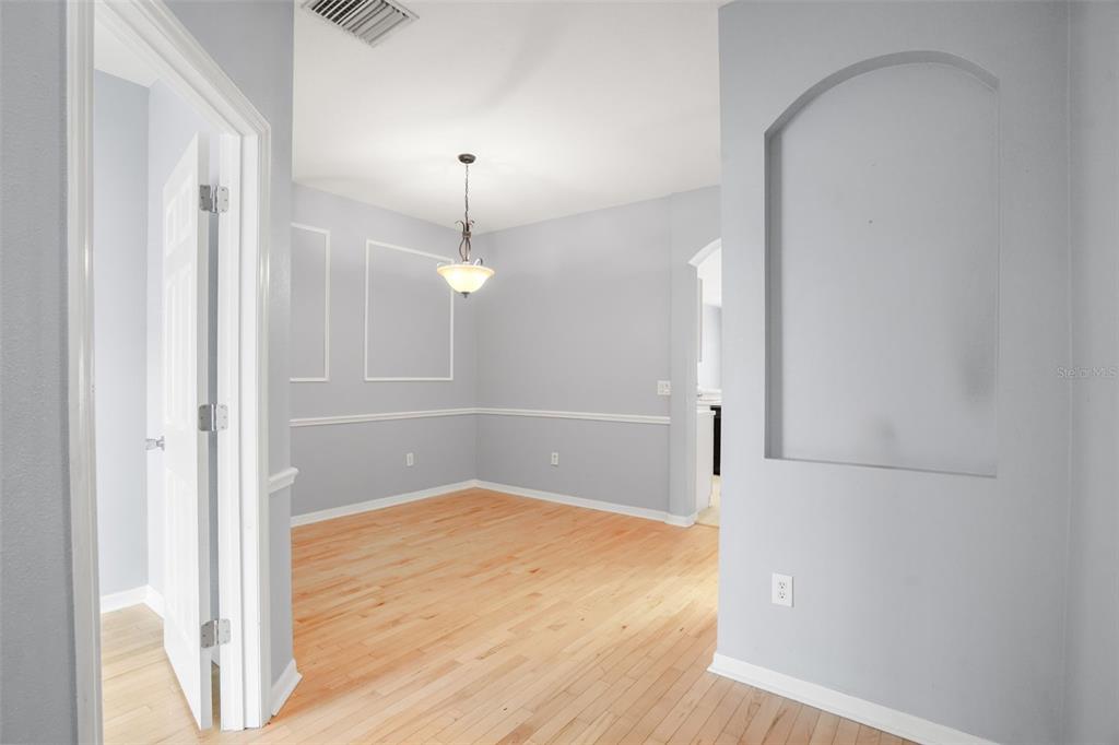 A dining room with light hardwood floors, gray walls, and a decorative arched wall niche — 13137 KINGS CROSSING DRIVE, GIBSONTON, FL