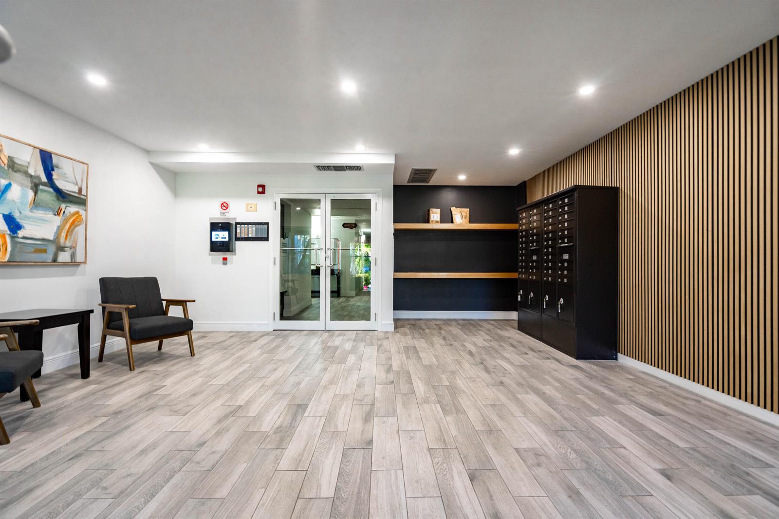 A modern lobby features wood-slat walls, mailboxes, a seating area, and glass double doors — 250 NE 20th Street # 5260, Boca Raton FL 33431, BOCA RATON, FL