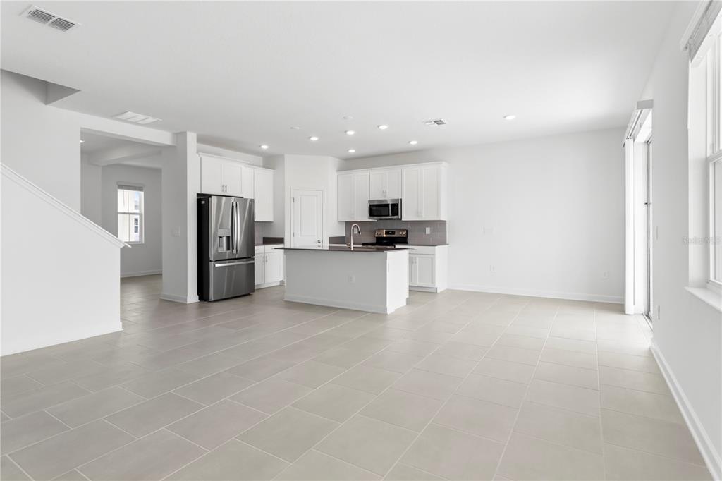 A modern kitchen with white cabinets, stainless steel appliances, and a central island — 5786 STEPHENS ROAD, ST CLOUD, FL