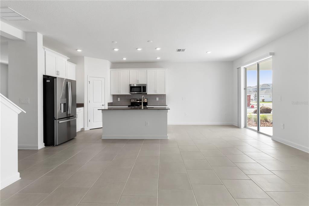 A modern kitchen features white cabinets, stainless steel appliances, and a central island with tile — 5786 STEPHENS ROAD, ST CLOUD, FL