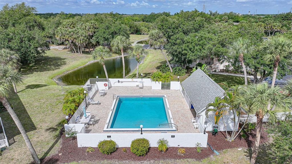 An aerial view of a rectangular swimming pool enclosed by a white wall and landscaping — 1051 FORREST NELSON BOULEVARD UNIT 201, PORT CHARLOTTE, FL