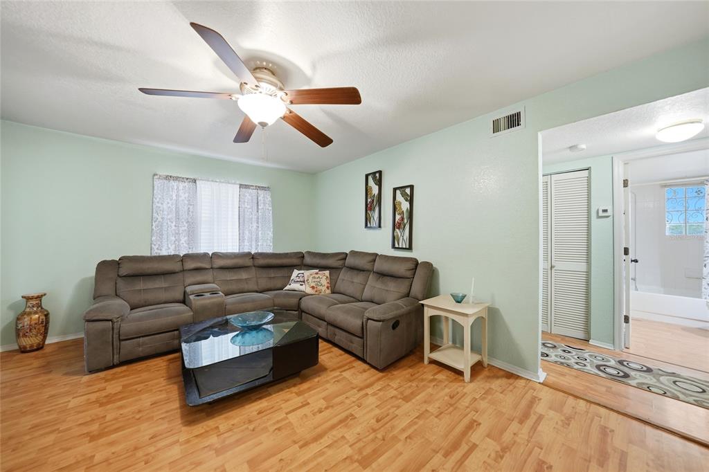 A living room features a grey sectional sofa, a glass coffee table, and wood flooring — 1051 FORREST NELSON BOULEVARD UNIT 201, PORT CHARLOTTE, FL
