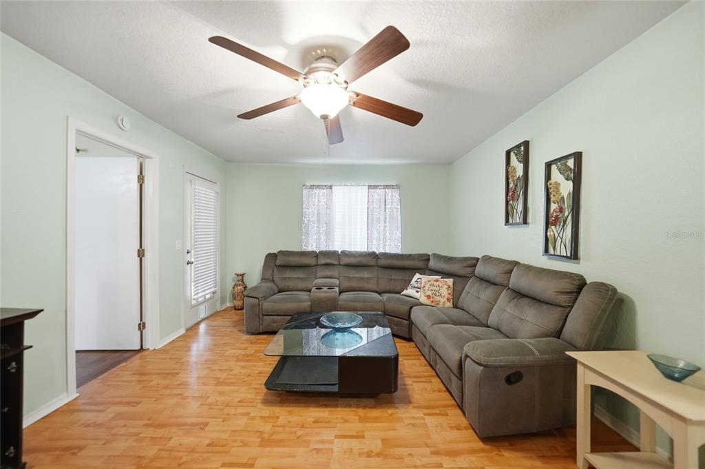 A living room features a grey sectional sofa, a glass coffee table, and wood flooring — 1051 FORREST NELSON BOULEVARD UNIT 201, PORT CHARLOTTE, FL