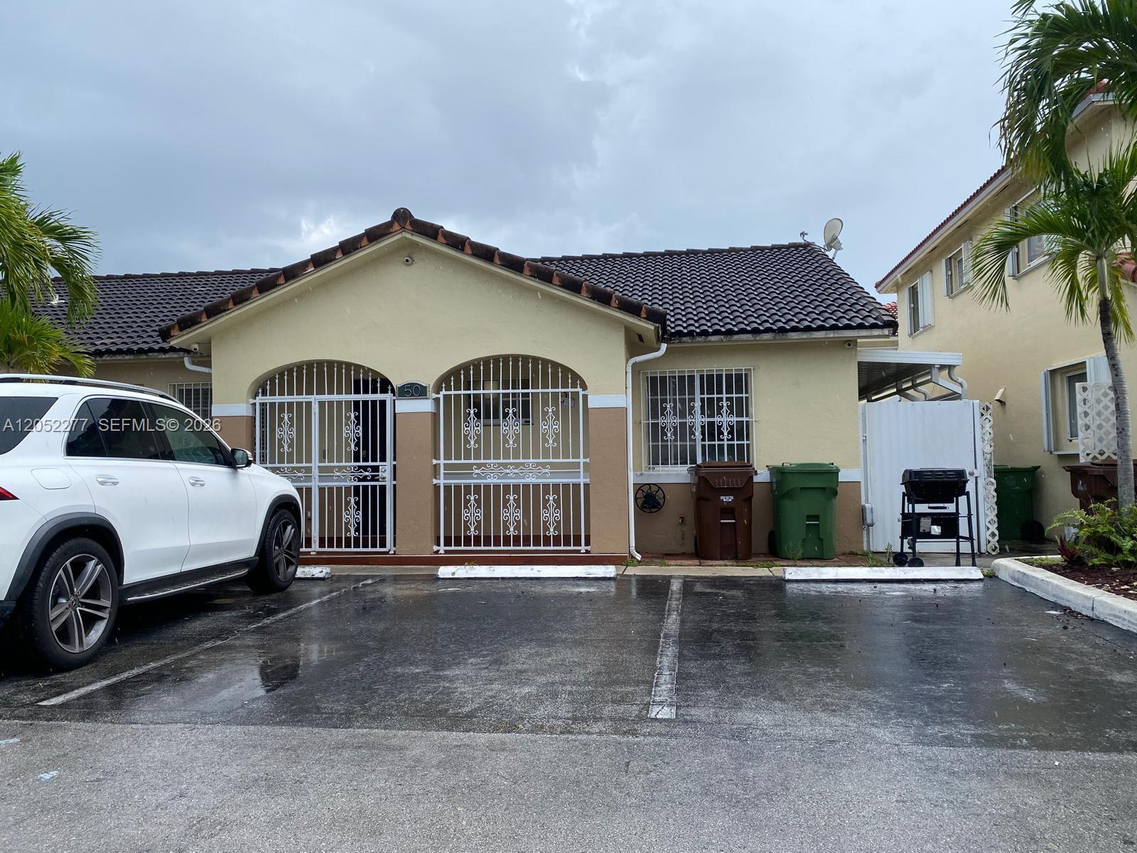 A single-story house with a tiled roof, white security gates, and a paved parking area — 7191 W 24th Ave, Hialeah FL 33016, HIALEAH, FL