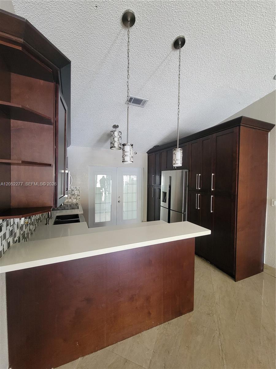 A kitchen features dark wood cabinetry, a white countertop, and two hanging pendant lights — 7191 W 24th Ave, Hialeah FL 33016, HIALEAH, FL