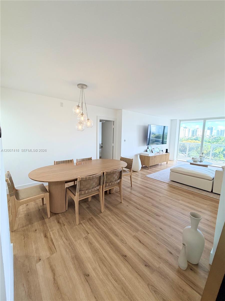 A dining area with an oval table and chairs sits adjacent to a living room — 3701 N Country Club Dr # 607, Aventura FL 33180, AVENTURA, FL