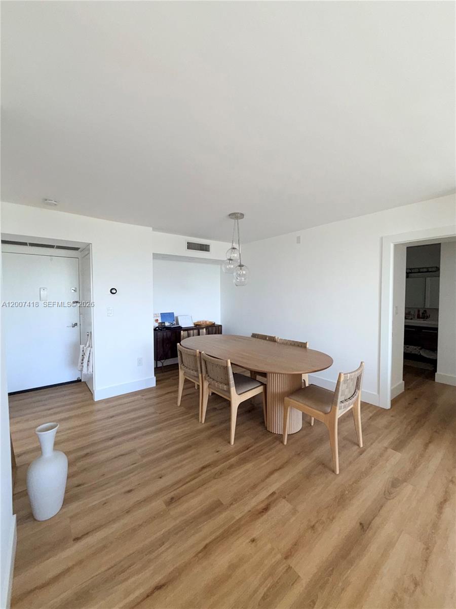 A dining area features a wooden oval table, four chairs, and light wood flooring — 3701 N Country Club Dr # 607, Aventura FL 33180, AVENTURA, FL