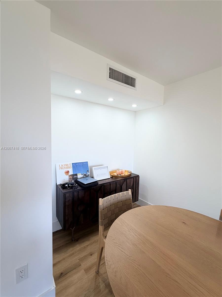 A dining area features a wooden table, a dark wood sideboard, and recessed ceiling lighting — 3701 N Country Club Dr # 607, Aventura FL 33180, AVENTURA, FL