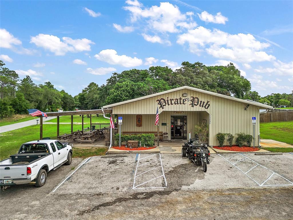 An exterior view of a single-story commercial building with a covered patio and parking lot — 25031 COUNTY ROAD 42, PAISLEY, FL