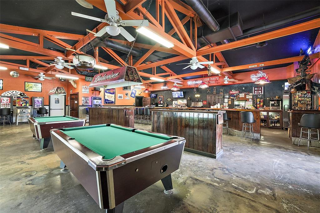 A bar interior featuring two pool tables, wooden counters, and exposed orange ceiling trusses — 25031 COUNTY ROAD 42, PAISLEY, FL