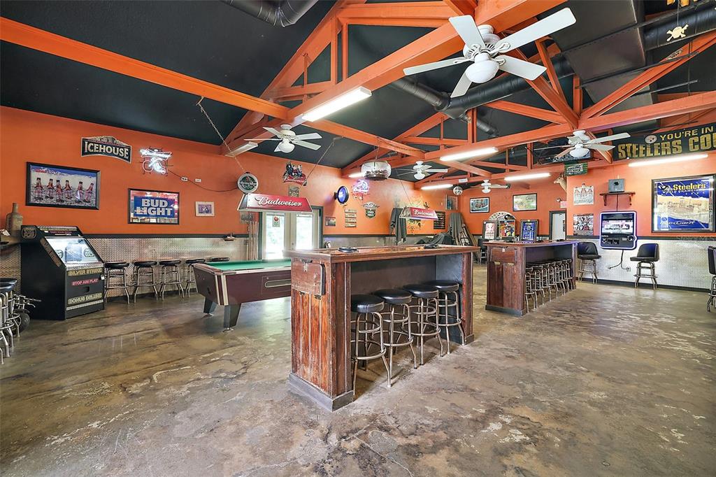 A spacious game room features a pool table, bar seating, and orange walls — 25031 COUNTY ROAD 42, PAISLEY, FL