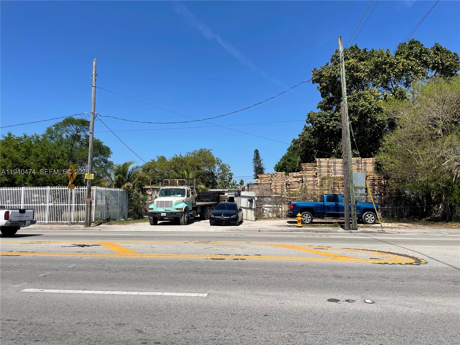 A flat, gravel-surfaced lot features a parked truck, a car, and a large pallet stack — 3021 NW 54th St, Miami FL 33142, MIAMI, FL