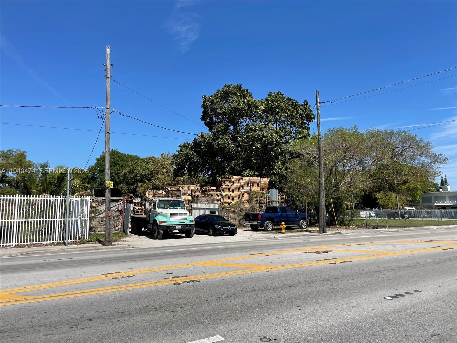 A truck and two cars are parked in front of a large stack of pallets — 3021 NW 54th St, Miami FL 33142, MIAMI, FL