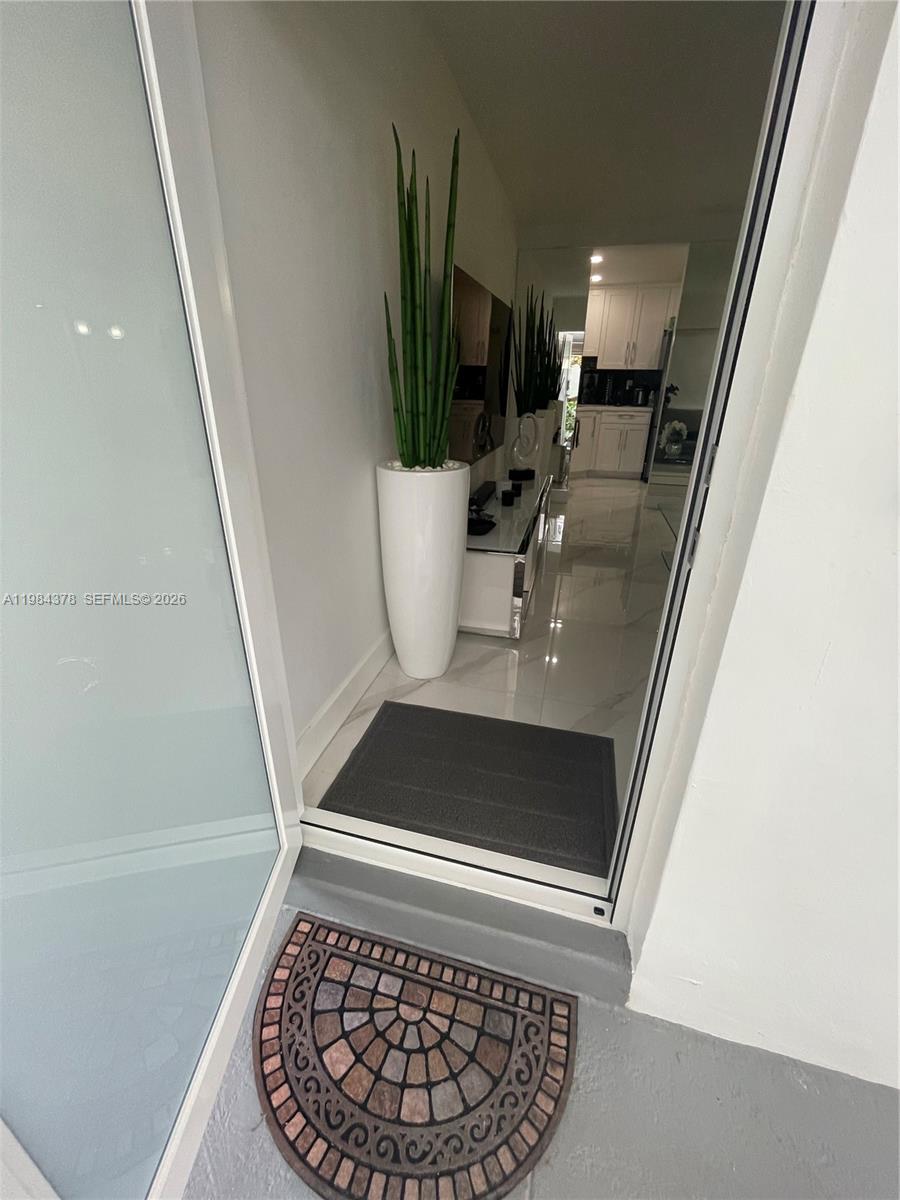 A doorway leads into a modern entryway with white tile floors and a tall plant — 926 Michigan Ave # 3, Miami Beach FL 33139, MIAMI BEACH, FL