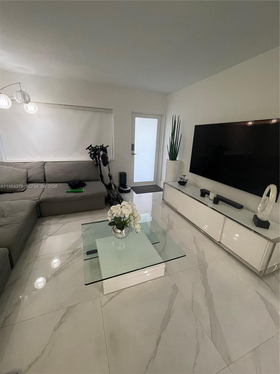 A modern living room features white marble-look tile floors, a gray sectional, and a television — 926 Michigan Ave # 3, Miami Beach FL 33139, MIAMI BEACH, FL