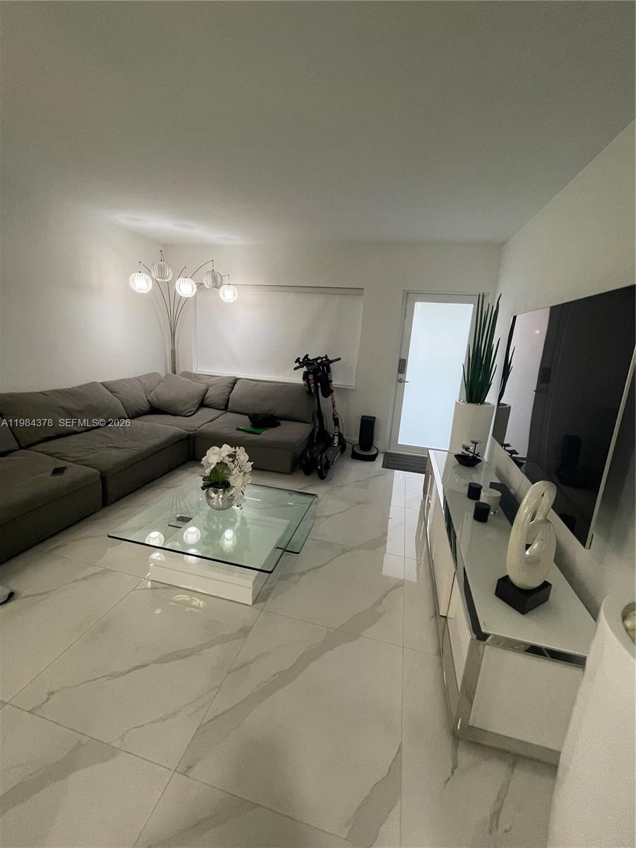 A modern living room features a grey sectional sofa, glass coffee table, and white tile flooring — 926 Michigan Ave # 3, Miami Beach FL 33139, MIAMI BEACH, FL