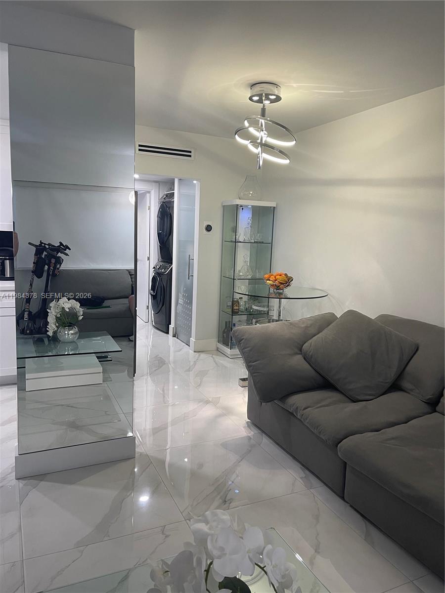 A living room features white marble-look tile floors, a grey sofa, and a mirrored wall — 926 Michigan Ave # 3, Miami Beach FL 33139, MIAMI BEACH, FL
