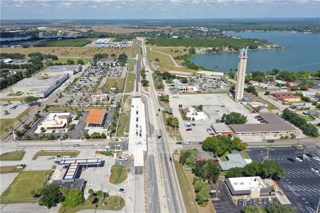 An aerial view shows a highway under construction with surrounding commercial buildings and a lake — 419 US 27 N, LAKE PLACID, FL