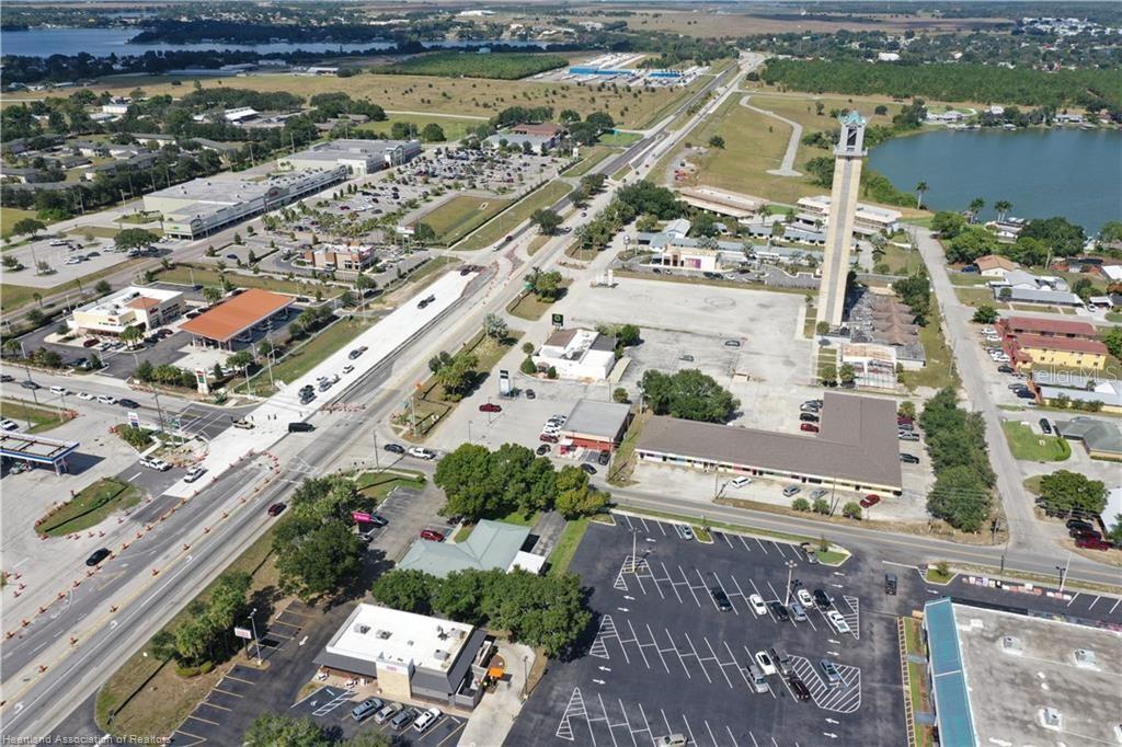 An aerial view shows a commercial area with a tall tower and a nearby lake — 419 US 27 N, LAKE PLACID, FL
