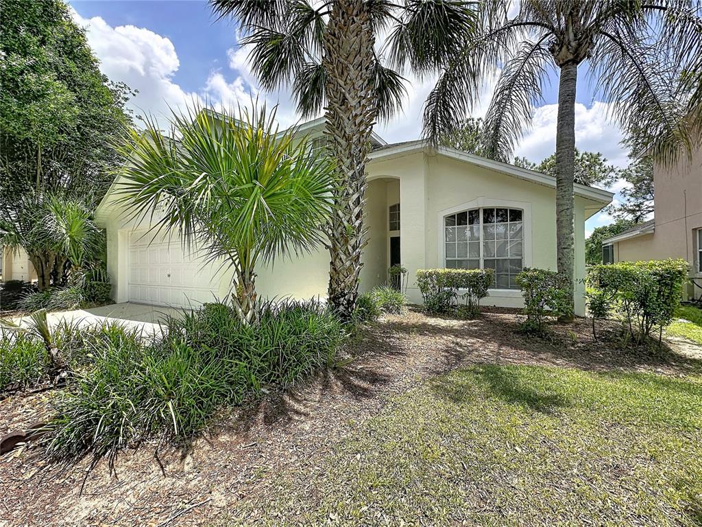 A light-colored house with a garage, palm trees, and a landscaped front yard — 2223 MALLORY CIRCLE, HAINES CITY, FL