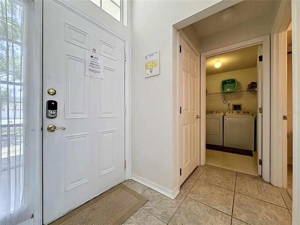 An entryway with a white front door, tiled floor, and an adjacent laundry room — 2223 MALLORY CIRCLE, HAINES CITY, FL