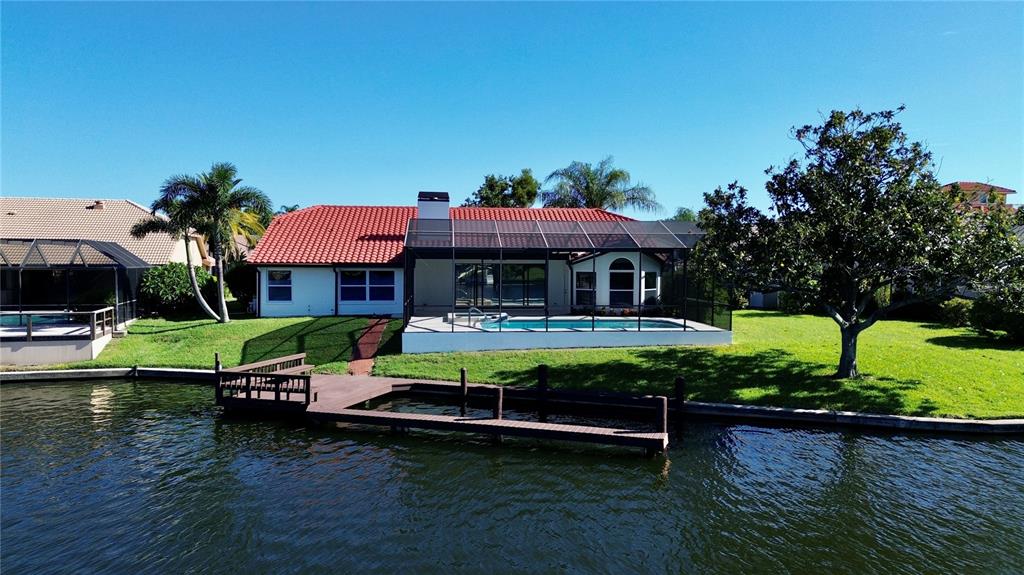 A waterfront house with a red tile roof, screened pool, and a wooden boat dock — 4804 LONGWATER WAY, TAMPA, FL