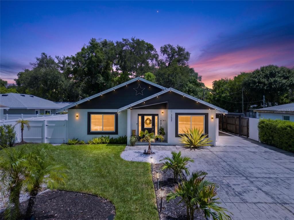 A single-story house with a dark gable, white exterior, and a paved driveway at dusk — 3227 W SPRUCE STREET, TAMPA, FL
