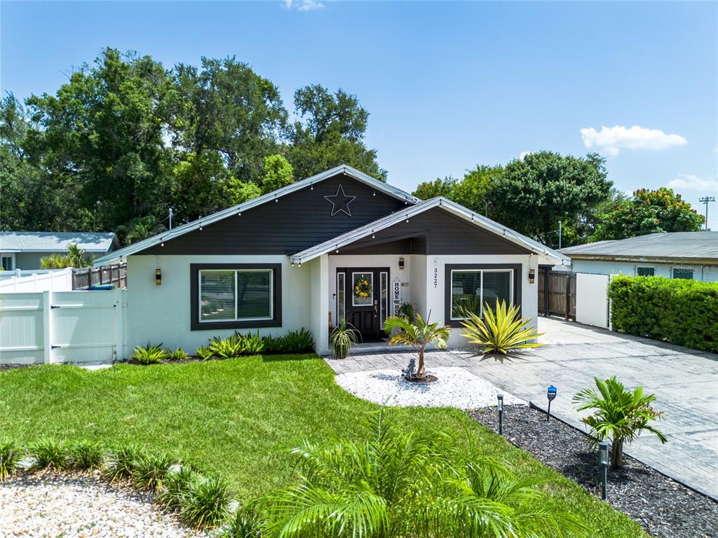 A single-story house with a white exterior, dark trim, a star decoration, and a driveway — 3227 W SPRUCE STREET, TAMPA, FL