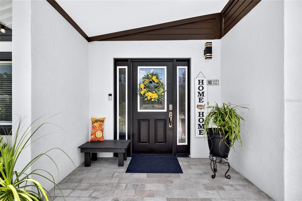 A front entryway features a black door with a yellow wreath and a small bench — 3227 W SPRUCE STREET, TAMPA, FL