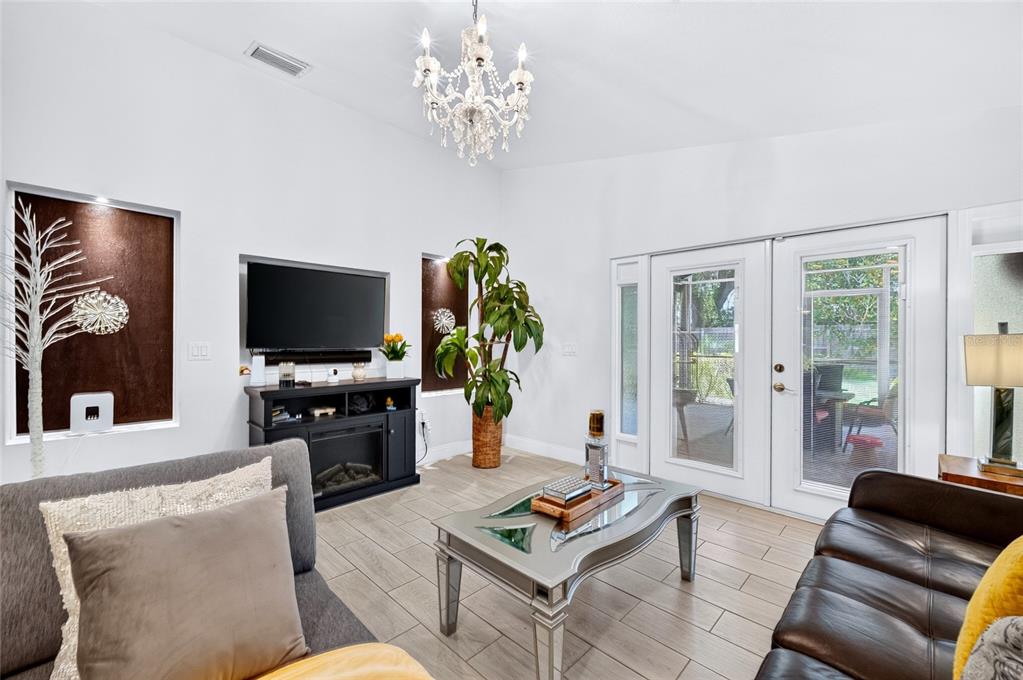 A living room features a chandelier, a television on a console, and glass patio doors — 3227 W SPRUCE STREET, TAMPA, FL