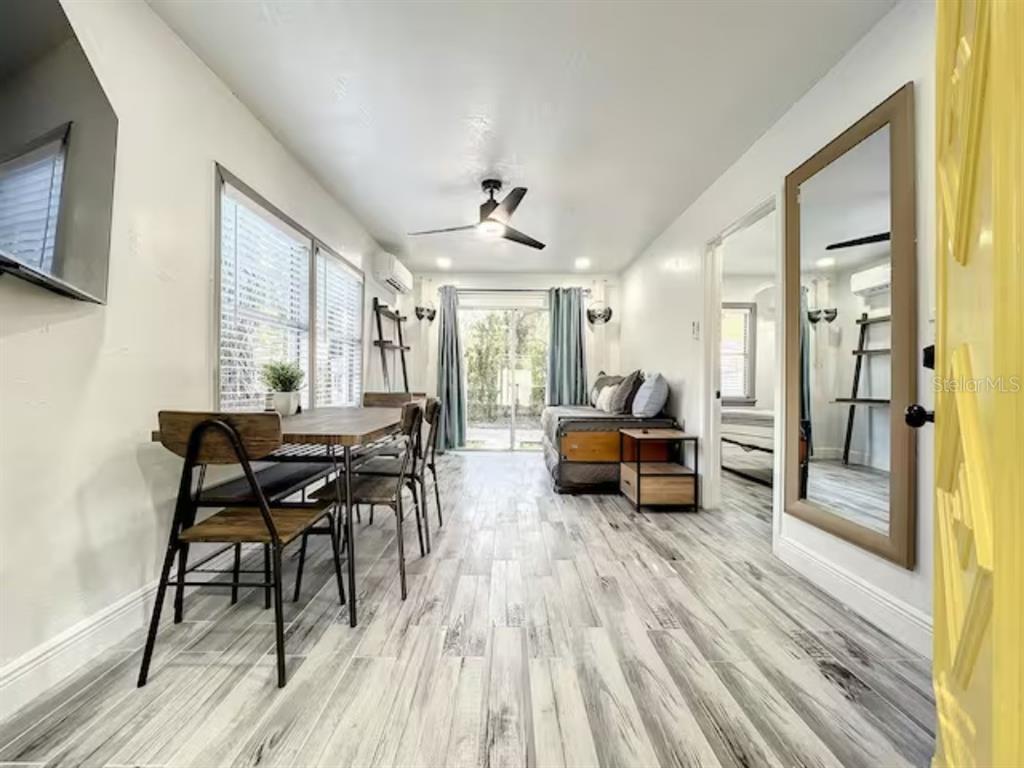 A living and dining area features wood-look flooring, a ceiling fan, and a large wall mirror — 2008 PAGE AVE UNIT 3, ORLANDO, FL