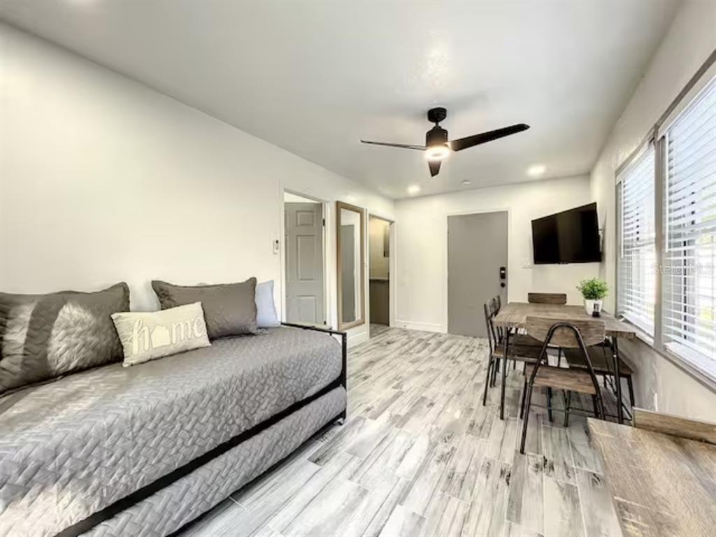A room features a daybed, a dining set, a ceiling fan, and light-colored wood-look flooring — 2008 PAGE AVE UNIT 3, ORLANDO, FL