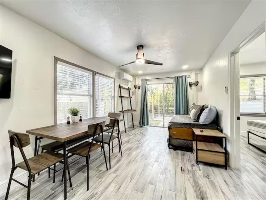 A living and dining area features wood-look tile flooring, a ceiling fan, and sliding glass doors — 2008 PAGE AVE UNIT 3, ORLANDO, FL