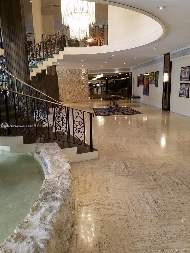 A grand foyer features a curved staircase, a stone fountain, and a large crystal chandelier — 5555 Collins Ave # 11U, Miami Beach FL 33140, MIAMI BEACH, FL