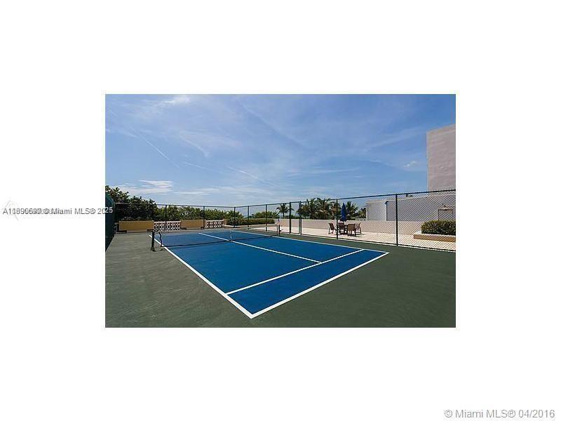 A blue tennis court with a net is enclosed by a chain-link fence outdoors — 5555 Collins Ave # 11U, Miami Beach FL 33140, MIAMI BEACH, FL