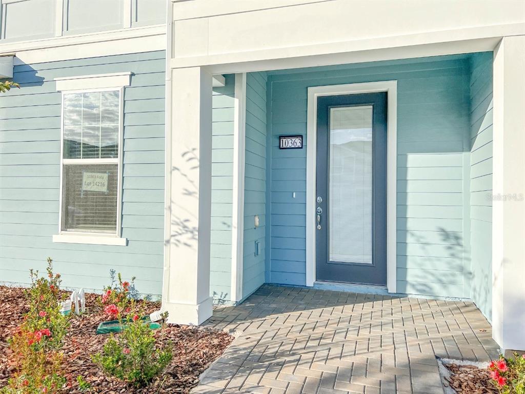 A light blue house exterior features a front door with a glass panel and pavers — 10363 FOLLY BEACH ROAD, ORLANDO, FL