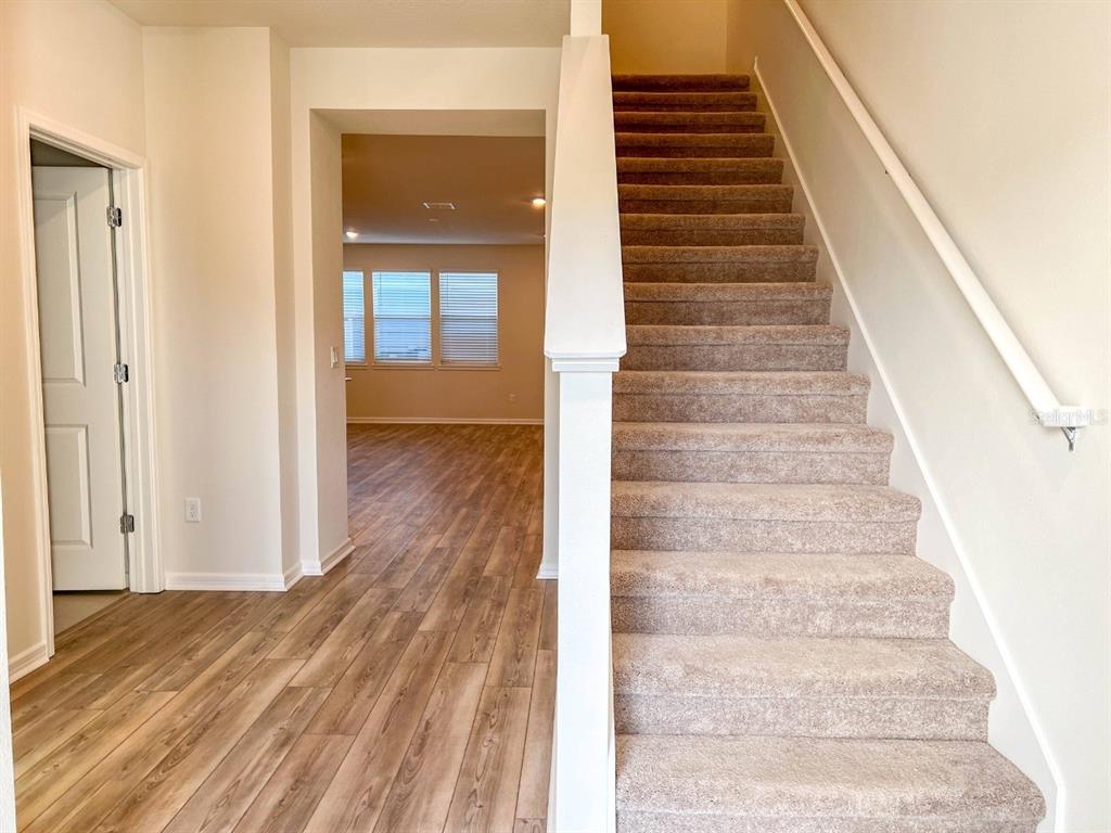 A carpeted staircase leads upward next to a doorway opening into a wood-floored room — 10363 FOLLY BEACH ROAD, ORLANDO, FL