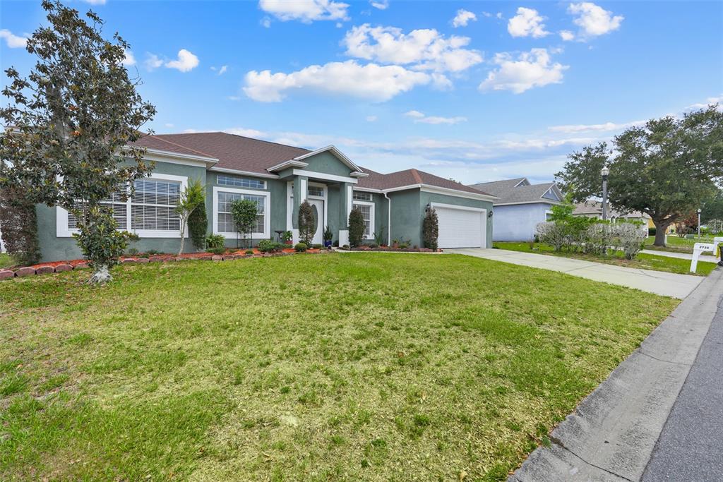 A single-story house with a green stucco exterior, a two-car garage, and a front lawn — 2735 BERKFORD CIRCLE, LAKELAND, FL