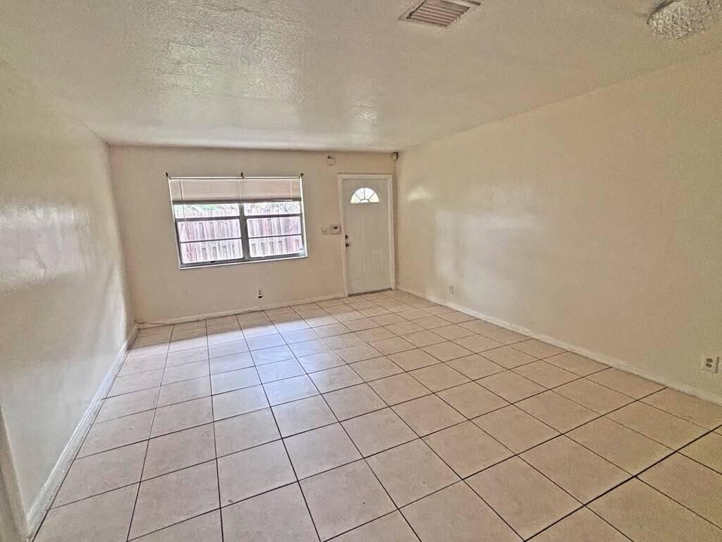 An empty room with beige tile flooring, white walls, a window, and a front door — 2620 Riverland Drive # 2, Fort Lauderdale FL 33312, FORT LAUDERDALE, FL