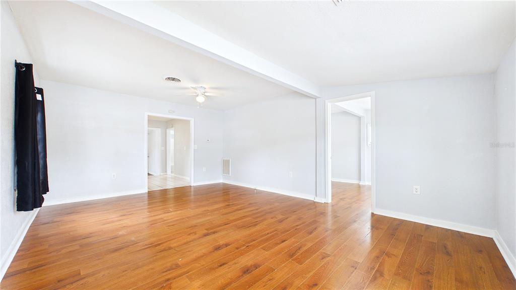 An empty room with light gray walls, wood-look flooring, and a white ceiling beam — 5001 RENA STREET N, ST PETERSBURG, FL