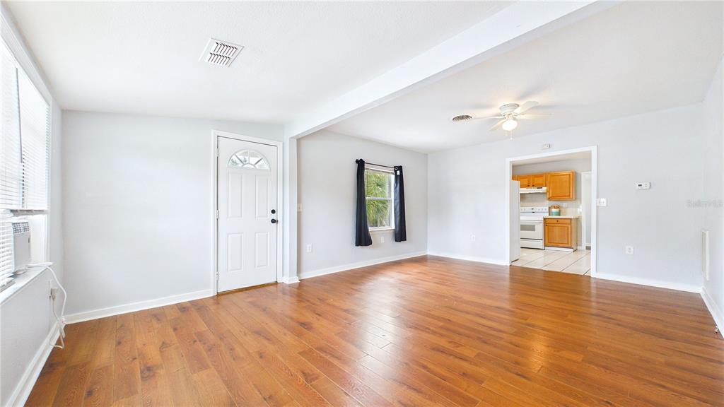 A living room with wood-look flooring, light gray walls, and an adjacent kitchen — 5001 RENA STREET N, ST PETERSBURG, FL