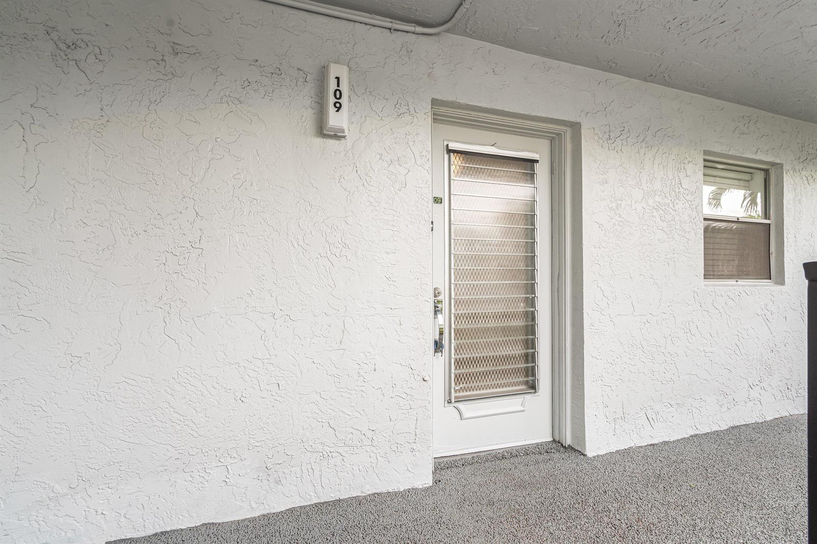 The exterior view shows a white stucco wall with a door labeled 109 and window — 3090 Holiday Springs Boulevard Unit 109, Margate FL 33063, MARGATE, FL