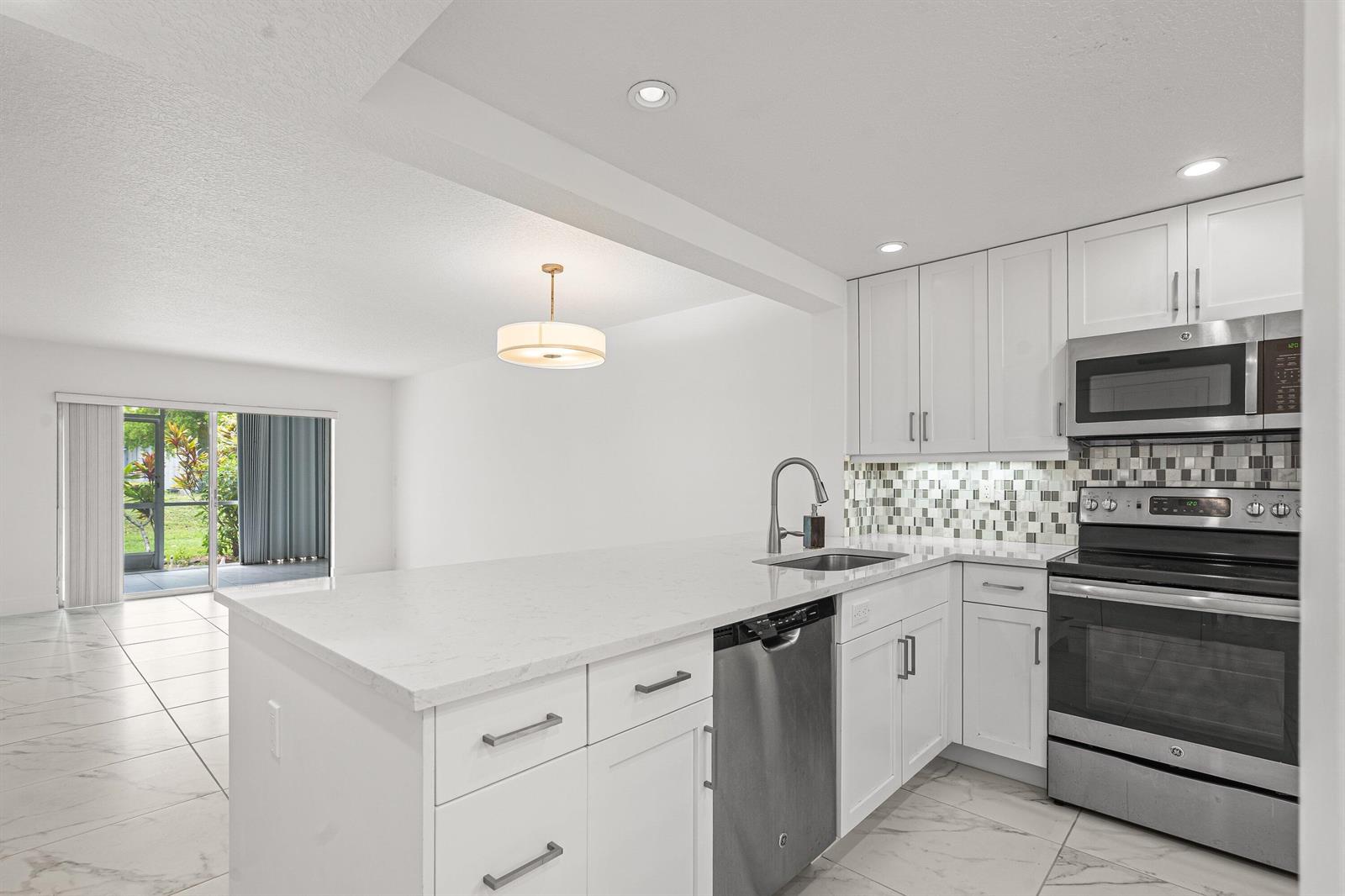 A modern kitchen with white cabinets, stainless steel appliances, and a quartz countertop island — 3090 Holiday Springs Boulevard Unit 109, Margate FL 33063, MARGATE, FL