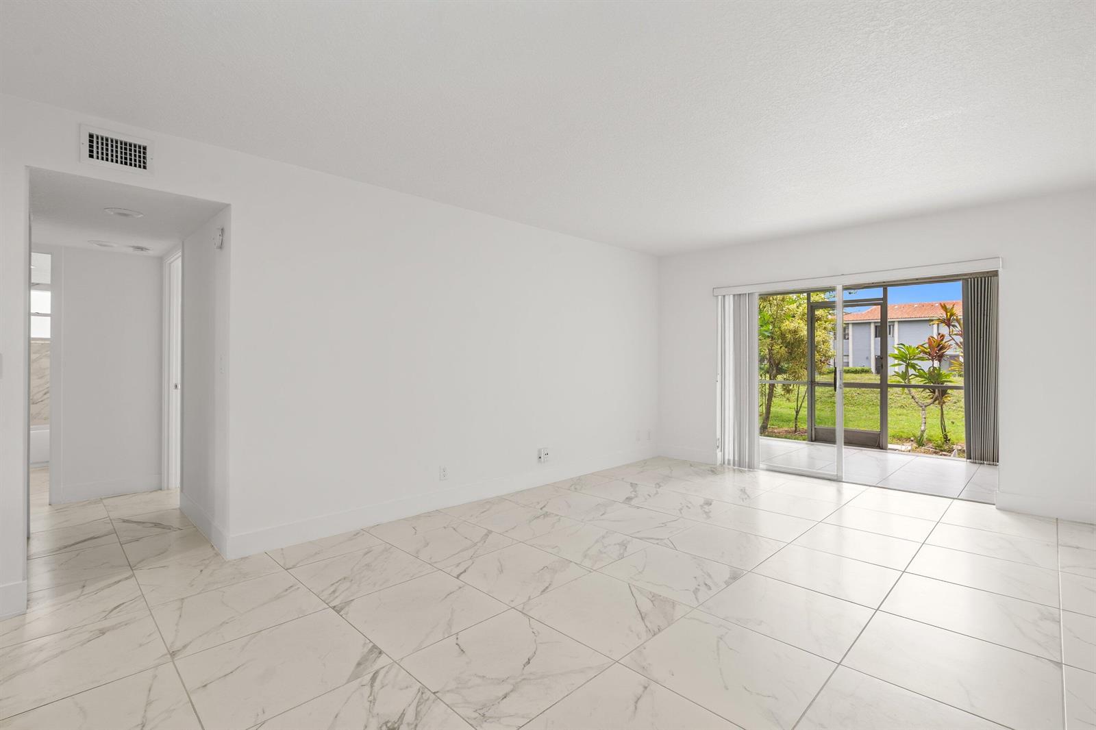 An empty room with white walls, white marble-look tile flooring, and a sliding glass door — 3090 Holiday Springs Boulevard Unit 109, Margate FL 33063, MARGATE, FL